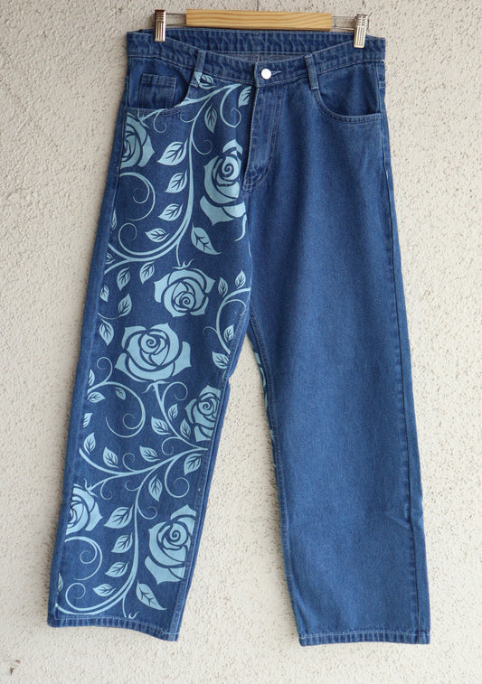 Blue jeans with floral pattern on waistband laid flat on a beige surface